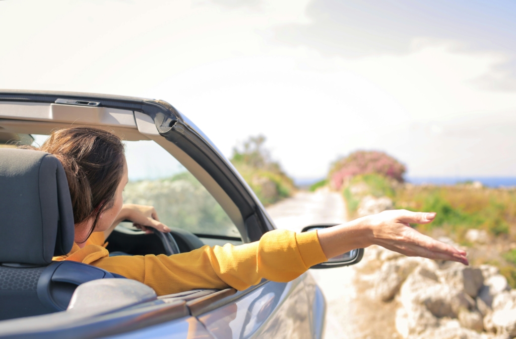 Female contractor driving with hand out of car window, symbolising freedom after closing a limited company and switching to self-assessment in the UK